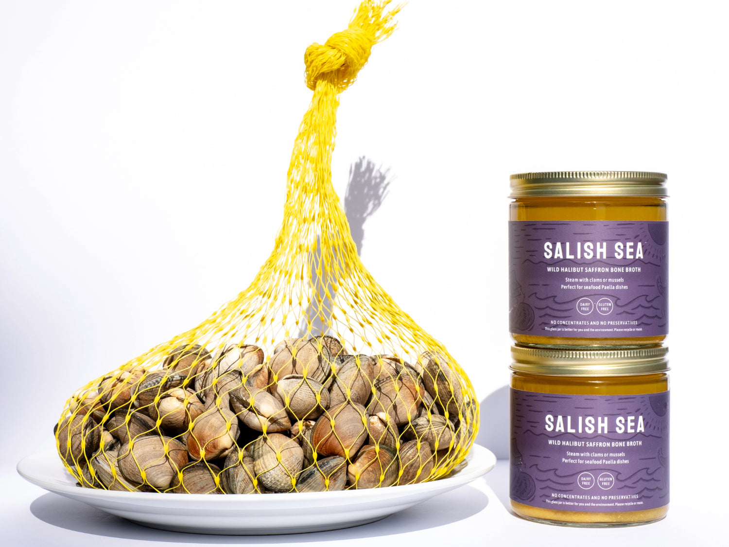 5 pounds of manila clams in a clam bag next to 2 jars of Yodelin wild halibut saffron bone broth